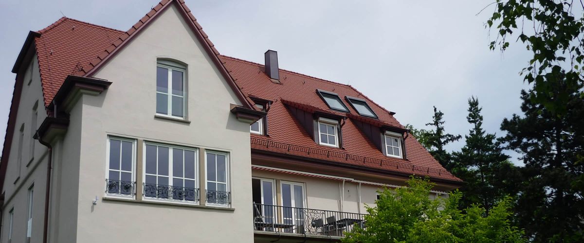 Komplettsanierung und Altbausanierung: Zweist&ouml;ckiges Haus mit rotem Ziegeldach und ausgebautem Dachgeschoss