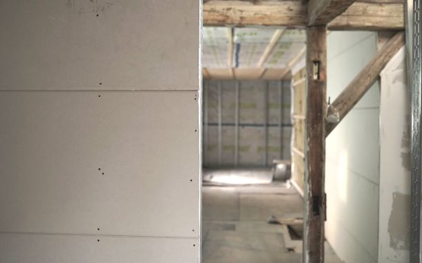 Raum im Umbau mit teilweise installierten Trockenbauwänden und sichtbaren Rohinstallationen.