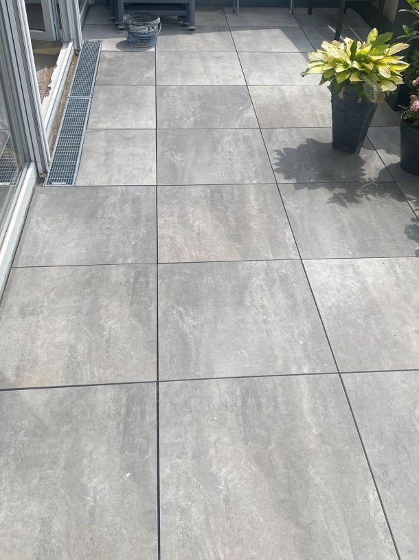 Sanierte Terrasse mit hellgrauen quadratischen Steinfliesen.