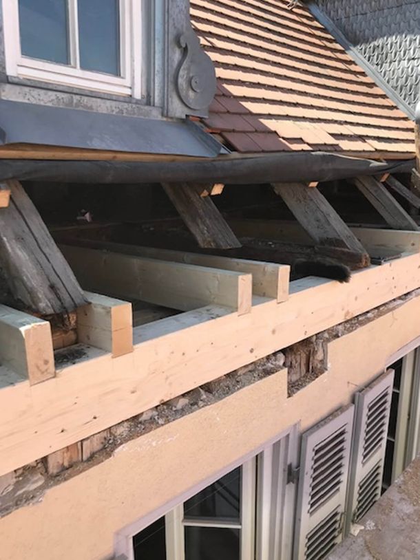 Reparaturarbeiten am Dach mit freiliegenden Holzbalken und neuen Dachziegeln