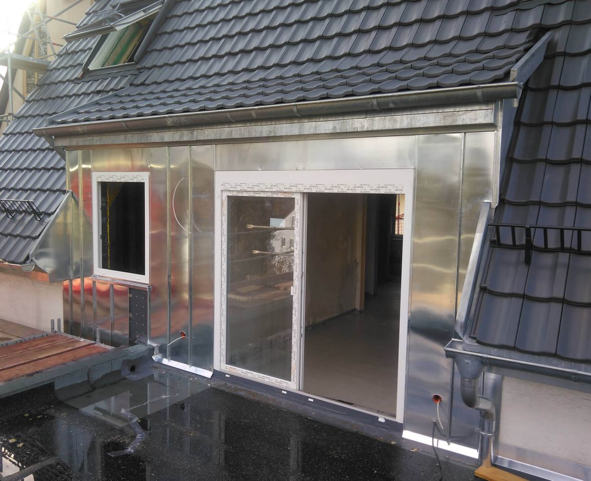 Sanierte Balkonanlage mit grauem Bodenbelag und Edelstahlgel&auml;nder an einem st&auml;dtischen Wohngeb&auml;ude.