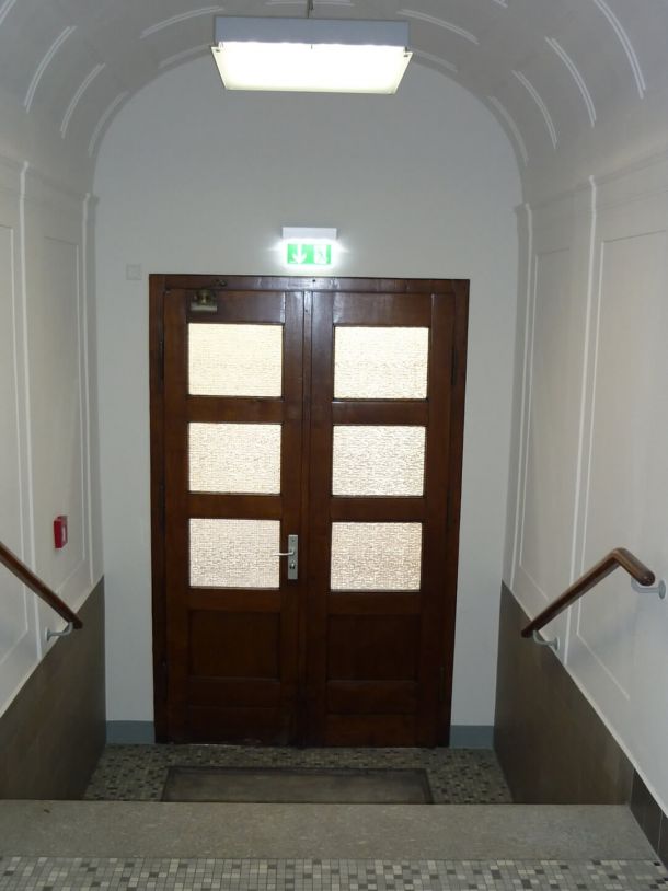 Eingangsbereich mit renoviertem Stuck an Wand und überhoher Decke im Altbau.