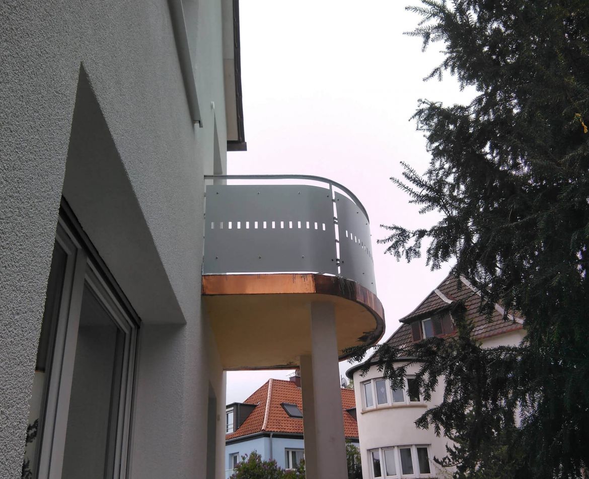 Runder sanierter Balkon mit modernem Metallgeländer und Stützsäule an einem zeitgenössischen Gebäude.