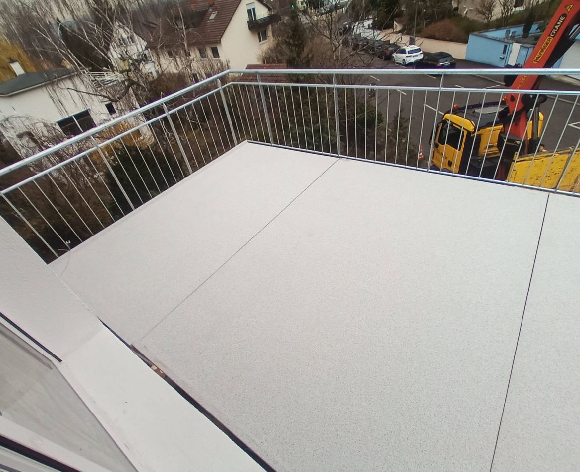 Neu sanierte Balkonanlage mit grauem Bodenbelag und Edelstahlgeländer an einem städtischen Wohngebäude