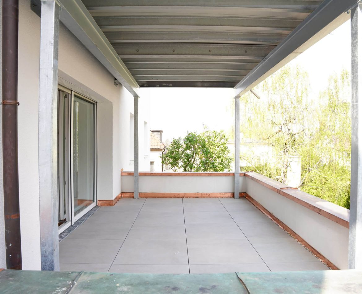 Frisch sanierte Balkonfläche mit grauen Fliesen.